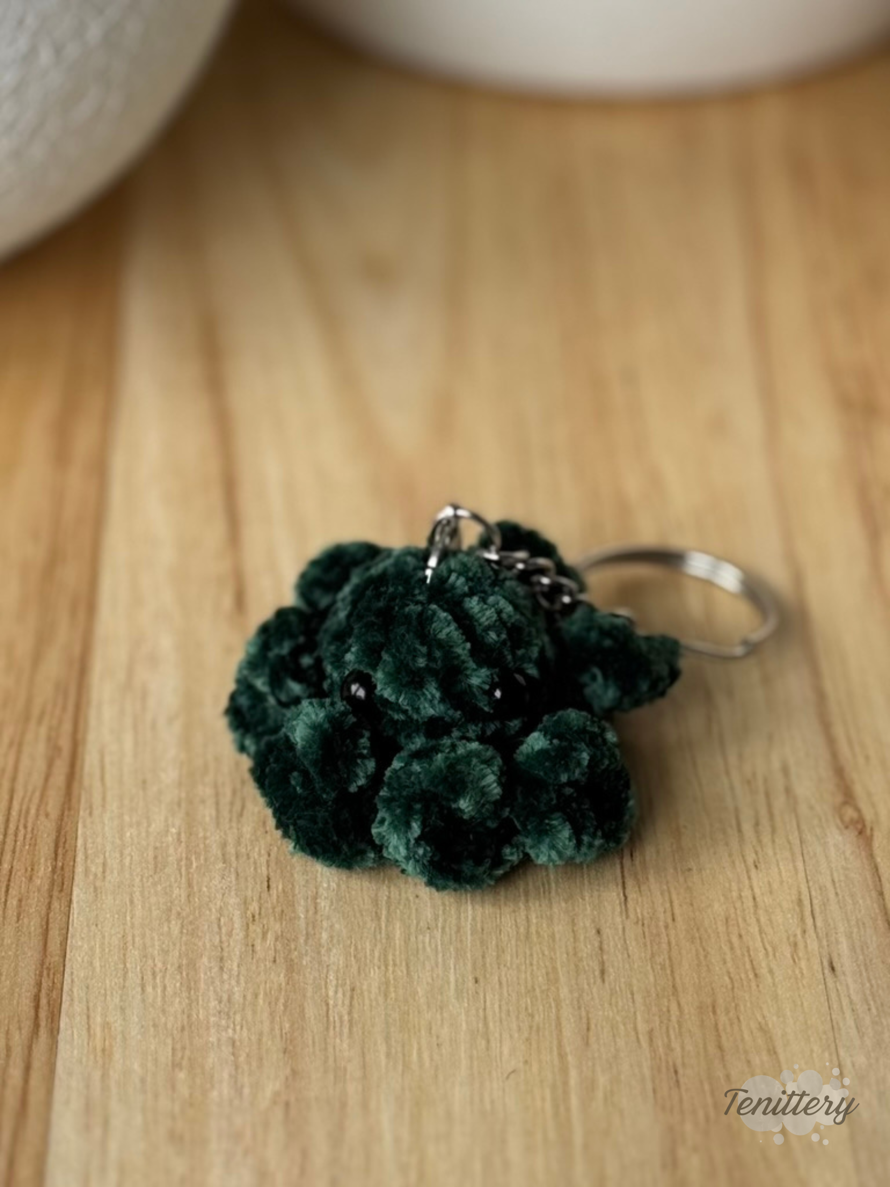 Háčkovaná klíčenka chobotnička ze sametové příze v tmavě zelené barvě s delšími chapadly.
