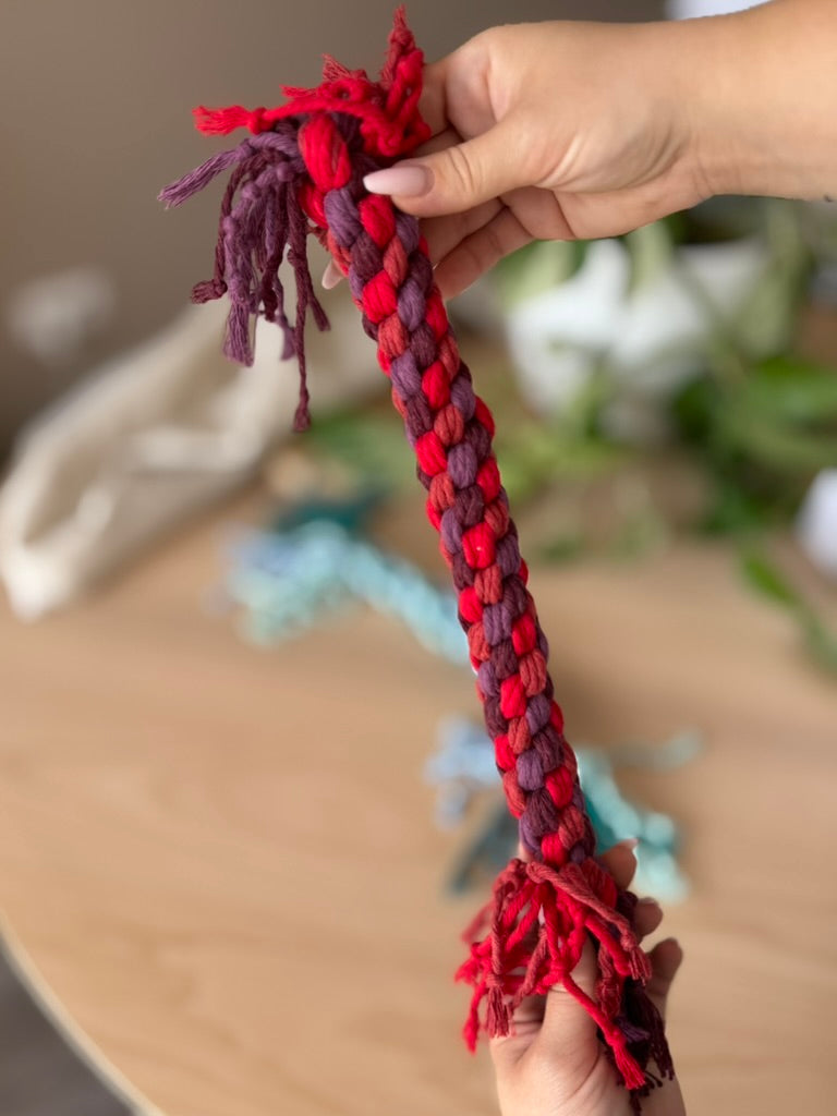 Macramé hračka pro psy - velká v tmavě červené barvě v ruce.
