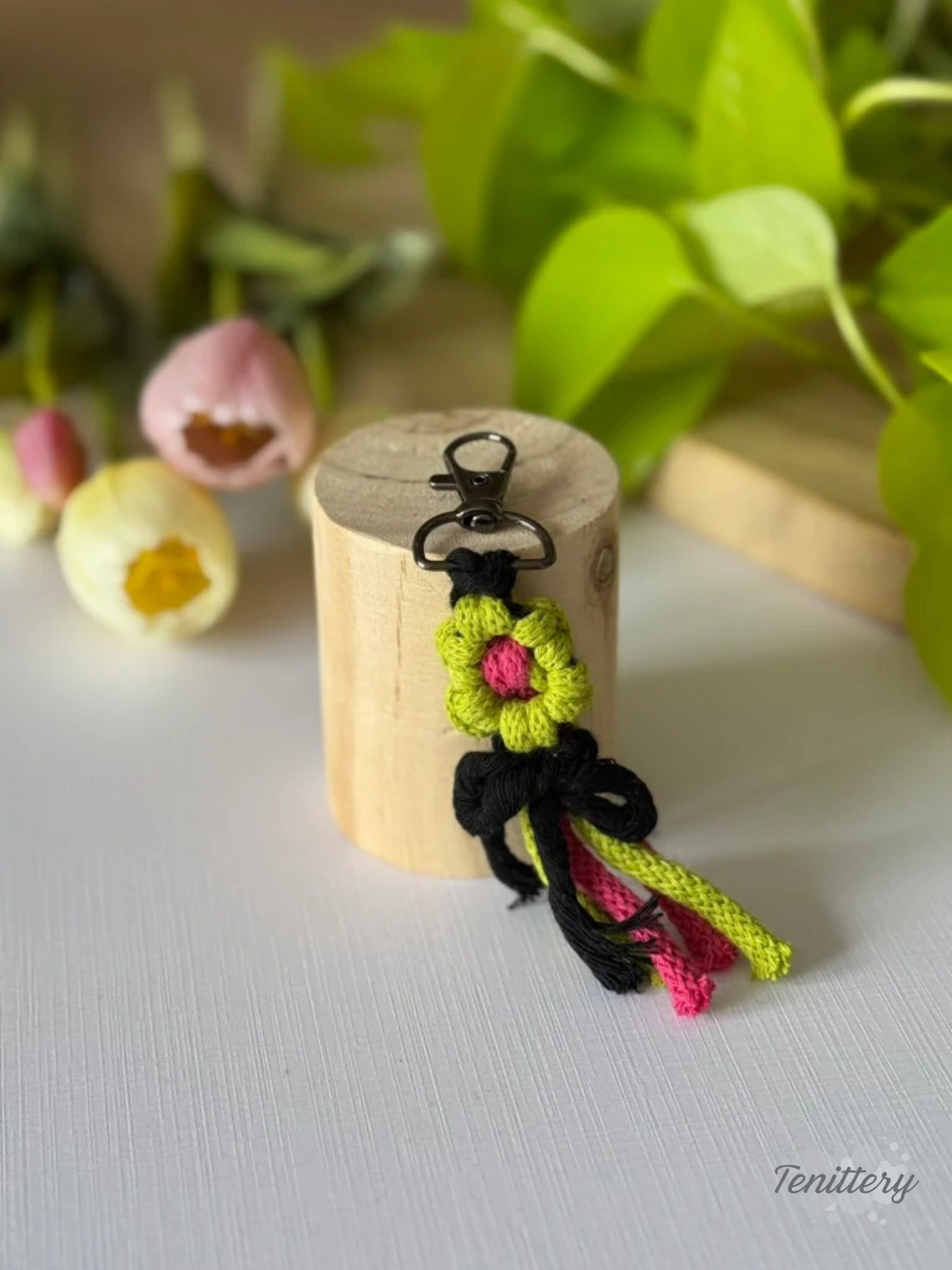Macramé klíčenka Kytička ve světle zelené a růžové barvě s černou mašličkou.