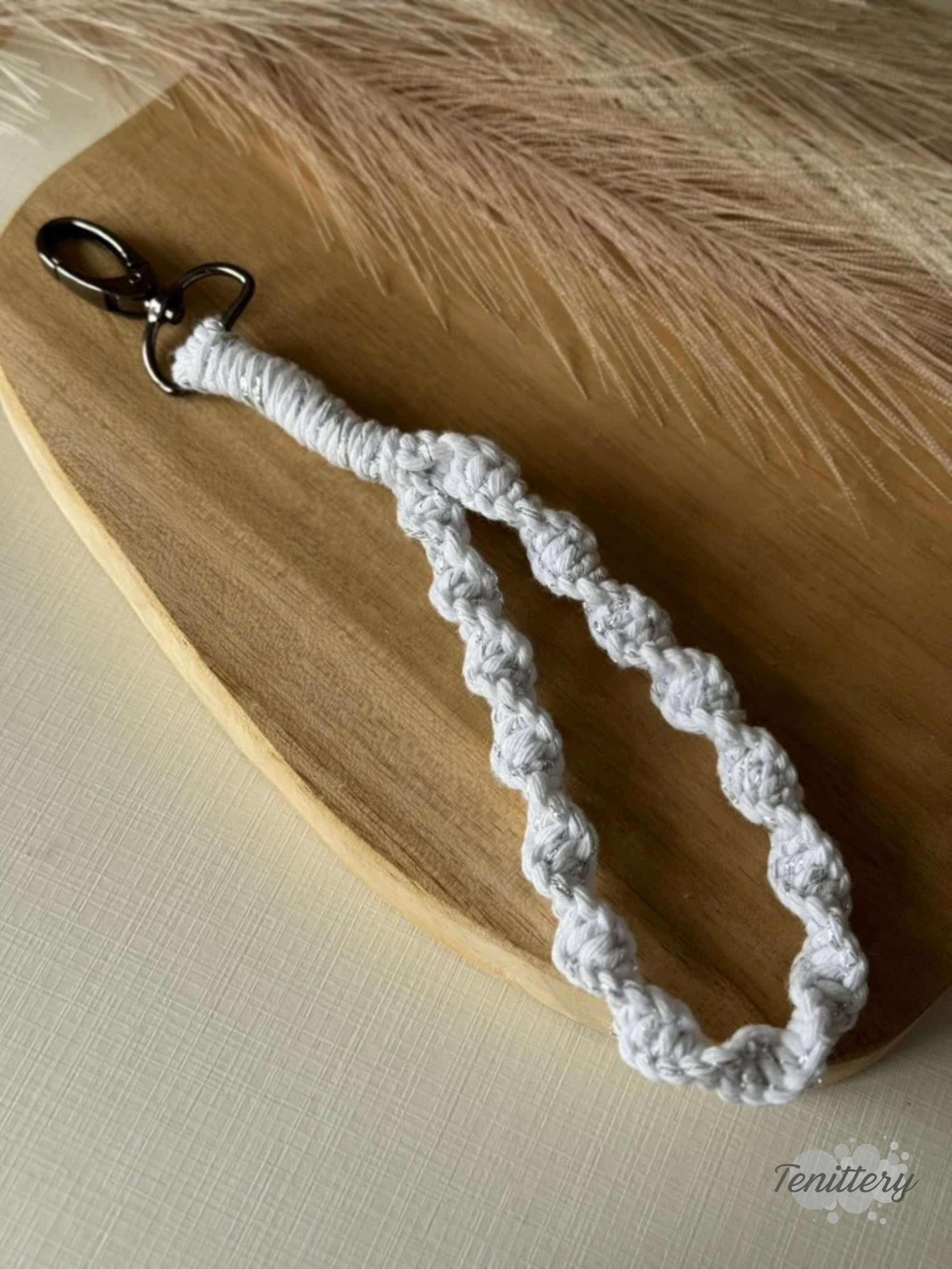 Macramé klíčenka Twist v bílé barvě se stříbrnou nitkou se silnější karabinou.