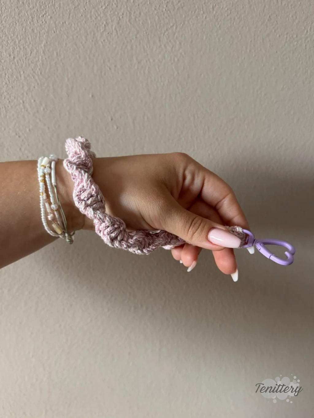 Macramé klíčenka Twist v žíhané růžové barvě s růžovou třpytivou nitkou s karabinou ve tvaru srdce v barvě lila - na ruce.