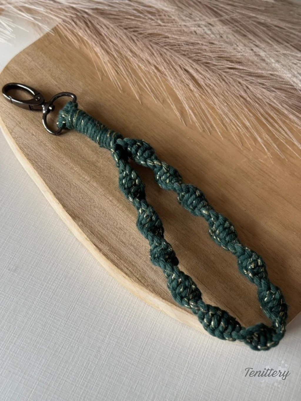 Macramé klíčenka Twist v tmavě zelené barvě se zlatou nitkou se silnější karabinou.