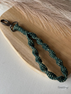 Macramé klíčenka Twist v tmavě zelené barvě se zlatou nitkou se silnější karabinou.