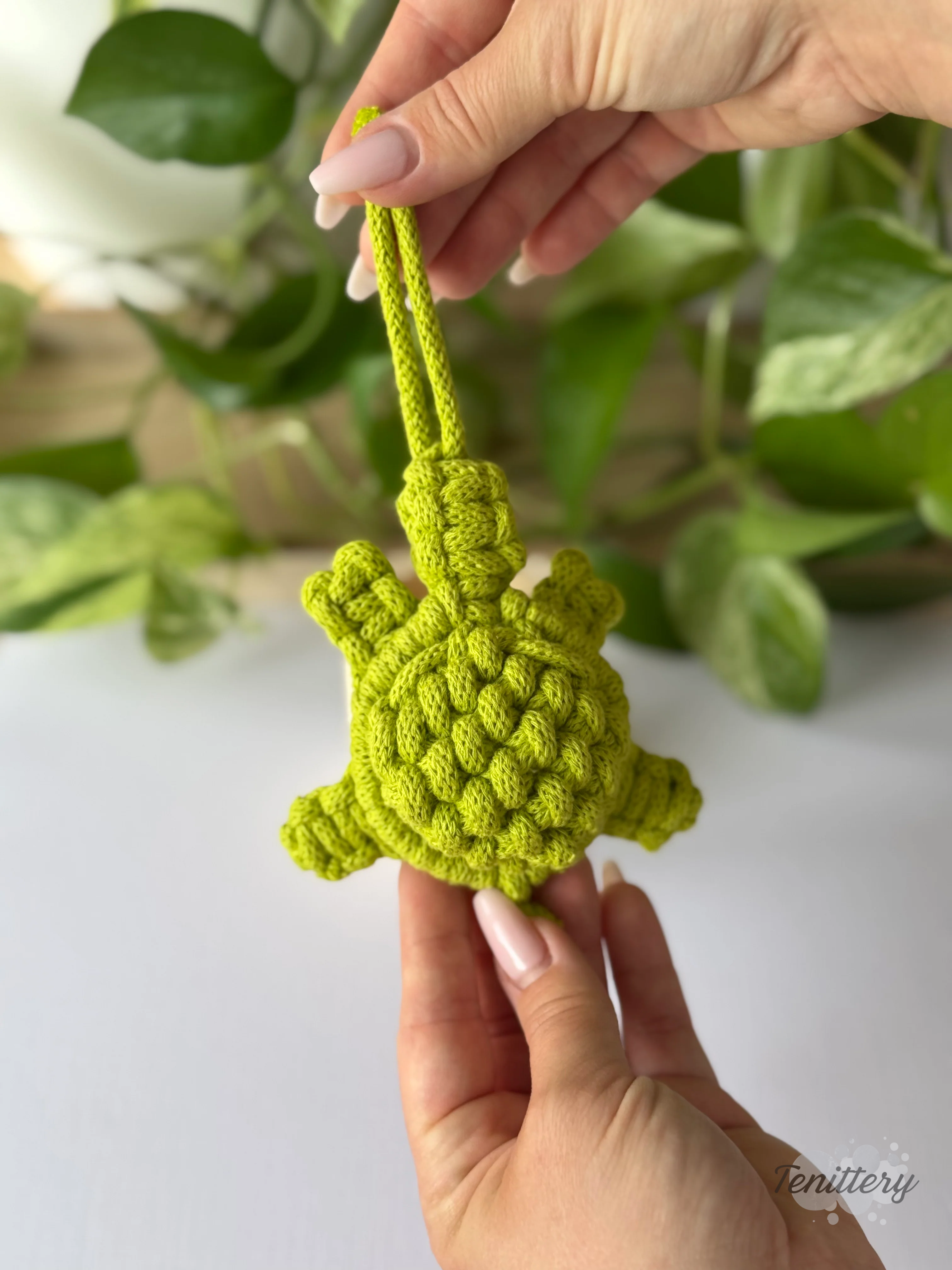 Macramé dekorace na zeď Želvička ve světle zelené barvě v ruce.